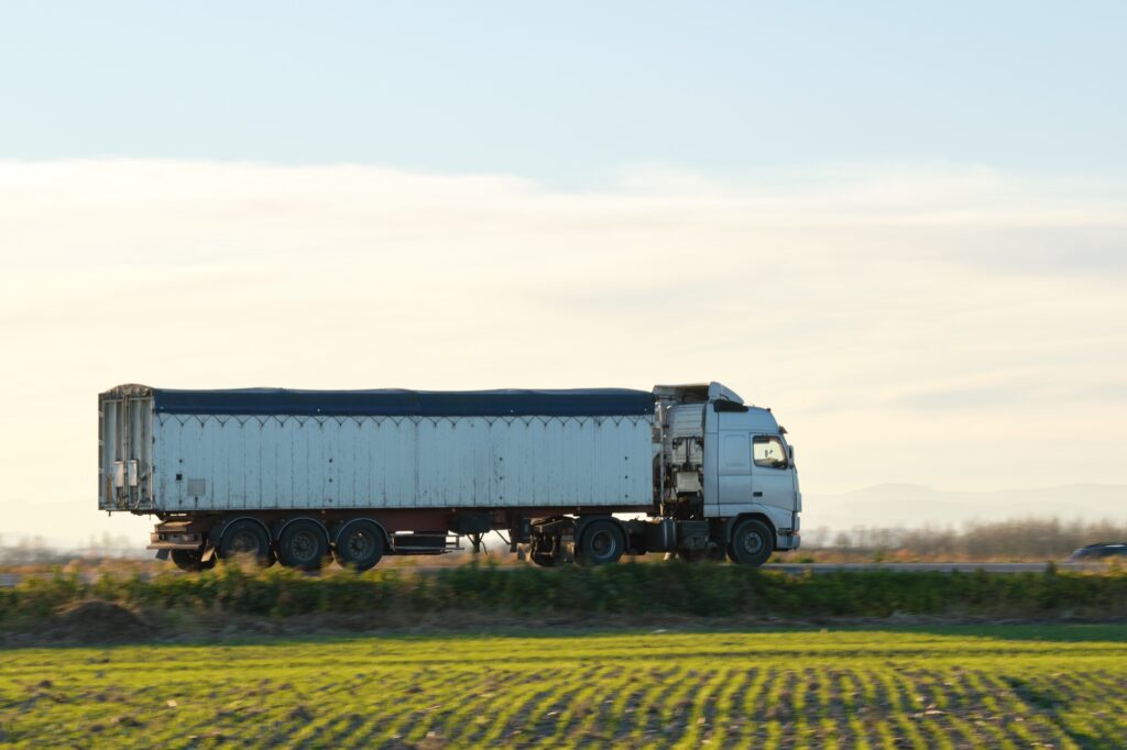 Semi-truck with tipping cargo trailer transporting sand from quarry driving on highway