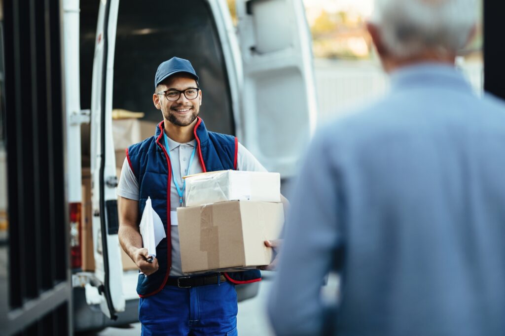 Young happy courier making a delivery to his customer.