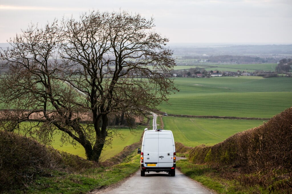Rear view of camper van driving down a country lane.